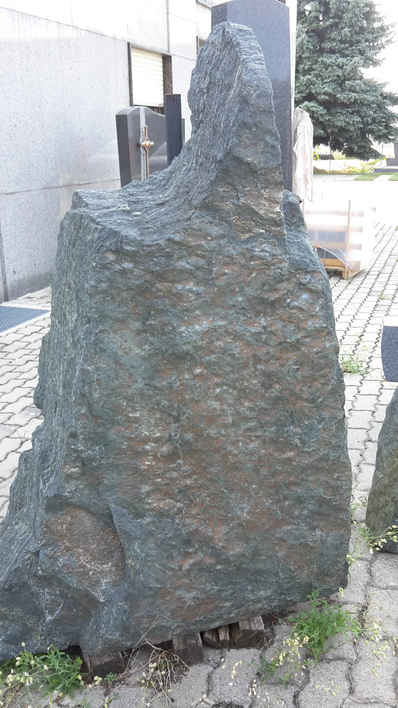Dunkler Naturstein-Rohling im Außenbereich des Steinmetzbetriebs
